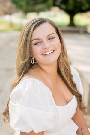 Portrait of woman in white summer top smiling outdoors.