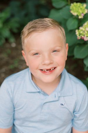 A series of joyful expressions captured in a light blue polo shirt against a natural green background.