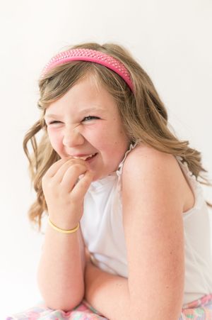 Four sequential photos showing someone wearing a pink headband laughing and covering their face with their hands.