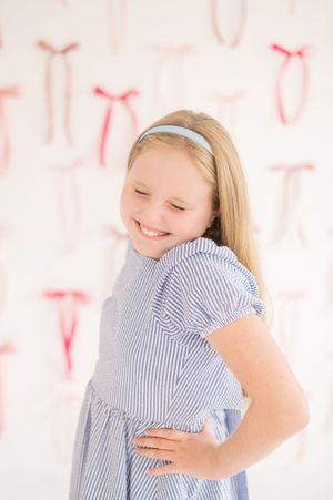 Portrait against pink and white background with decorative bows.