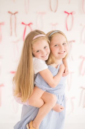 Portrait against pink and white background with decorative bows.