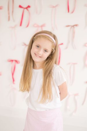 Portrait against pink and white background with decorative bows.