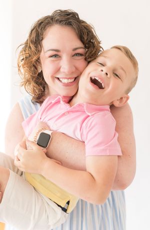 A joyful moment captured between a parent and child laughing together against a white background.