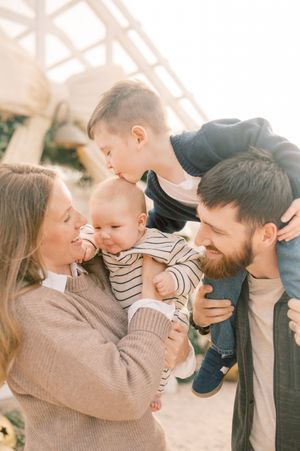 A loving family shares tender moments together in a series of warm, candid outdoor photographs.