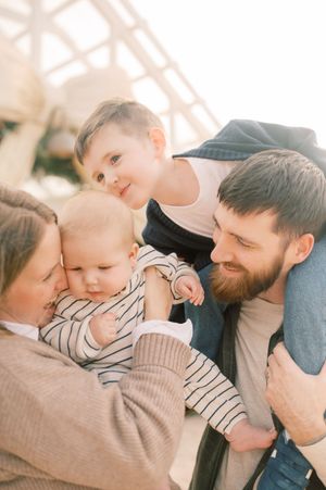 A tender family moment captured in warm sunlight as they gather close together and share affection with a baby.
