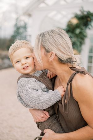 A tender moment between parent and child sharing laughter and embraces in an outdoor setting.
