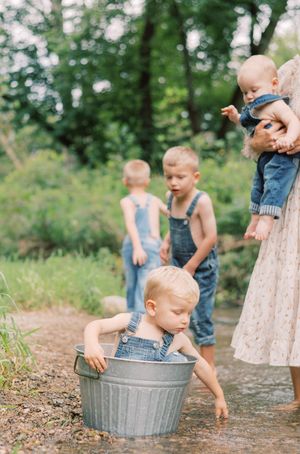 Children play and splash in metal wash tubs filled with water on a warm summer day outdoors.