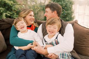 A candid family moment shows joyful laughter while sitting together on a couch with brown pillows.