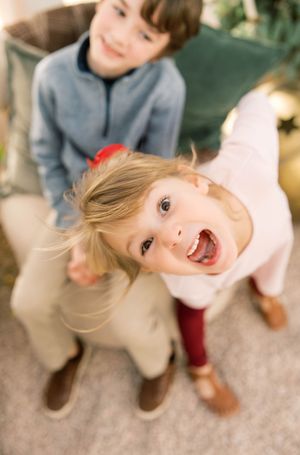 A playful child in a gray sweater spins and dances on a carpeted floor with joyful energy.