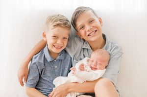 A loving family lying together on white bedding while sharing tender moments and smiles.