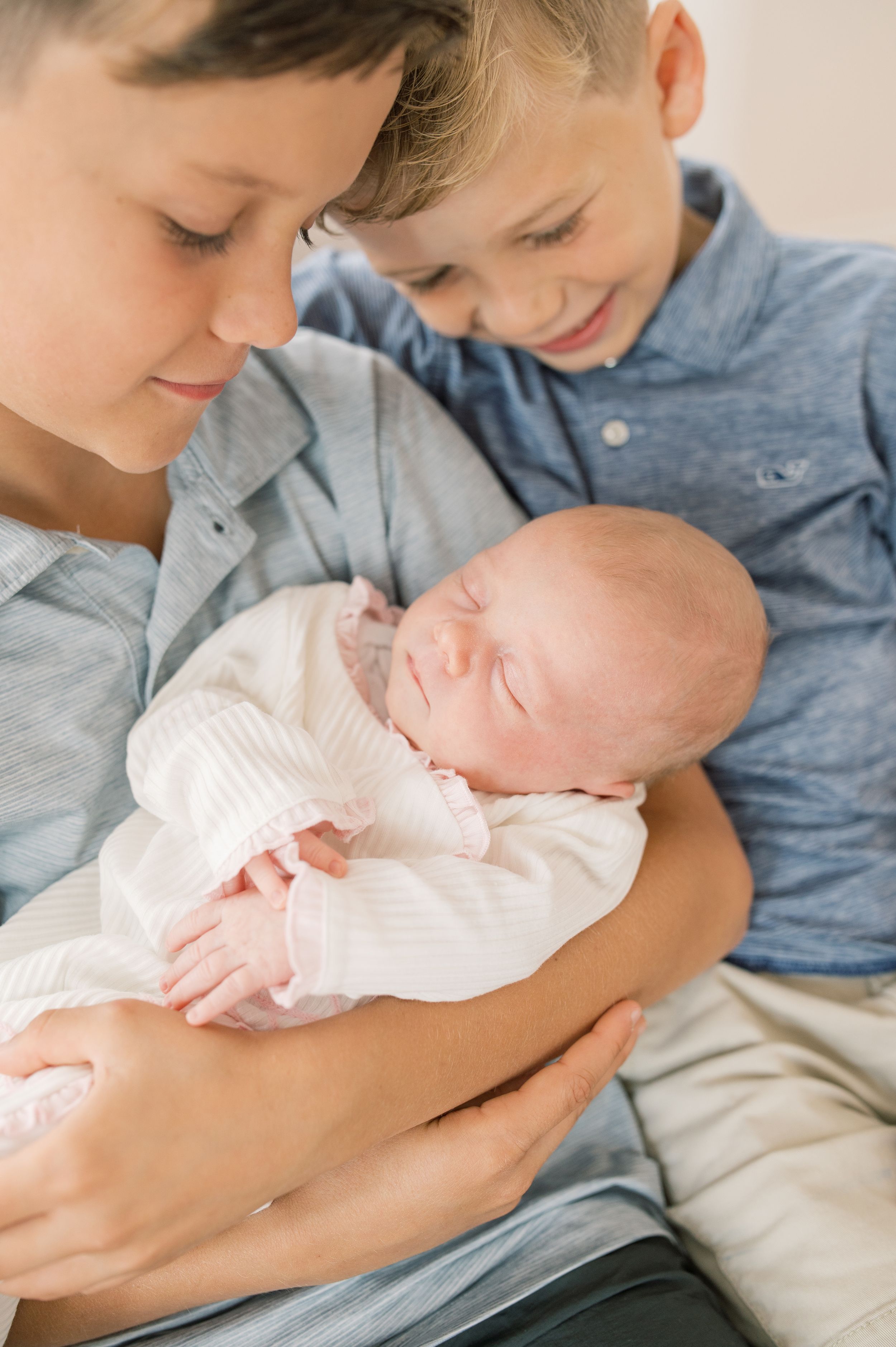 Three tender moments show siblings bonding with a newborn baby wearing a white dress.