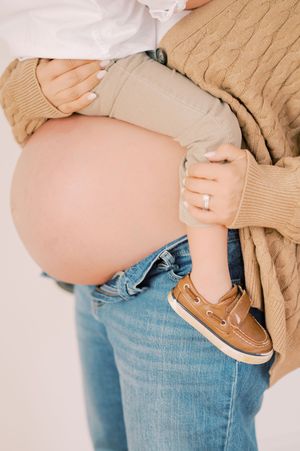 Close-up of pregnant belly with hands wearing cozy sweaters.