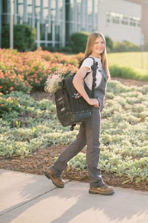 Progressive shots of a child in gray overalls playing and posing in a garden with blooming flowers and greenery.