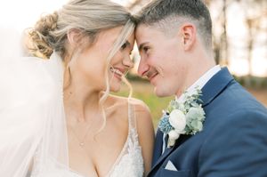 A close-up romantic moment between newlyweds with delicate blue floral boutonniere details.