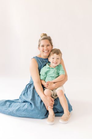 A heartwarming studio portrait showing a tender moment between parent and child against a light background.