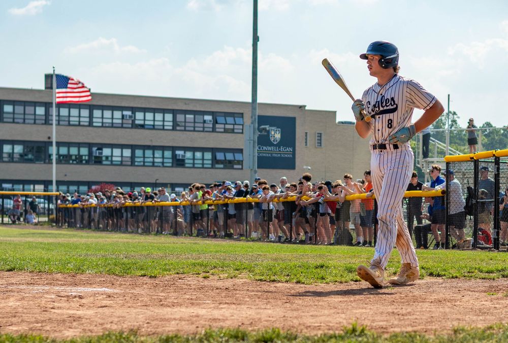 Conwell-Egan Catholic High School baseball player Tommy Kalita, wearing a batting helmet and holding a bat, walks toward home plate.