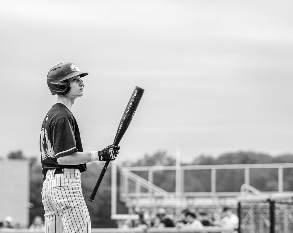 Black and white photo of Conwell-Egan Catholic High School player Gavin Hartley, wearing a batting helmet and holding a bat, looking up.