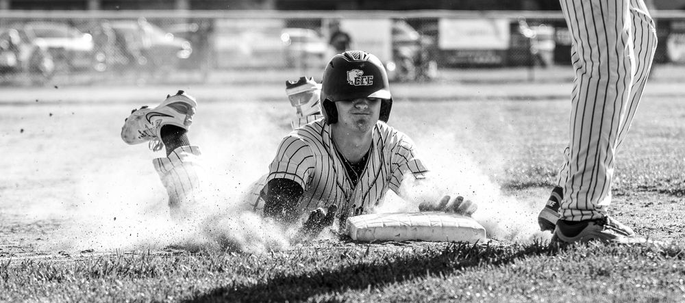 A black and white image of Chase Garofalo, of Conwell-Egan Catholic High School, sliding into third base in a cloud of dirt.