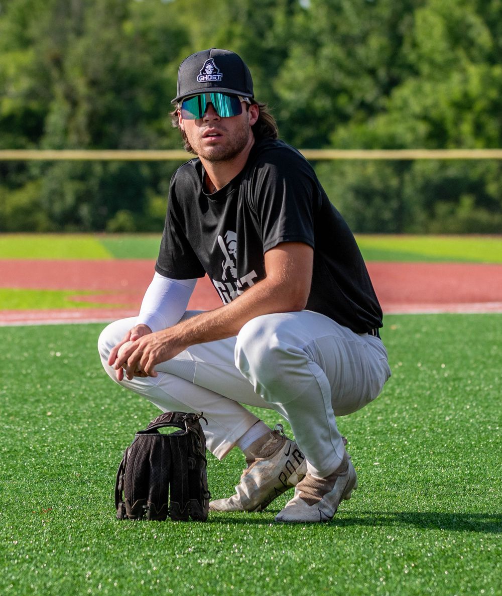 An unidentified Bucks County Ghost baseball player squatting while his glove is propped up next to him.