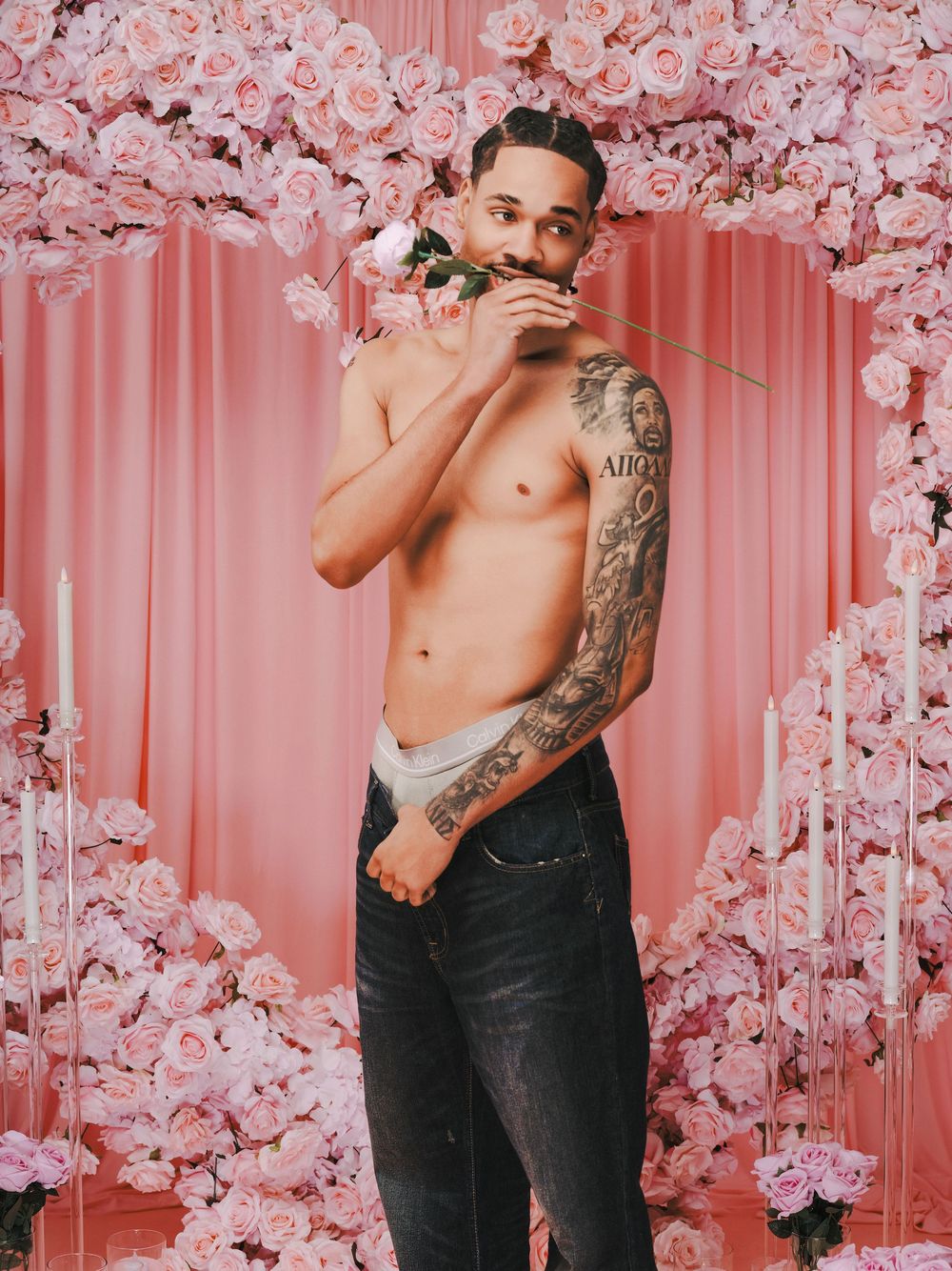 Artistic portrait series with pink cherry blossoms against coral backdrop featuring shirtless model in dark jeans.
