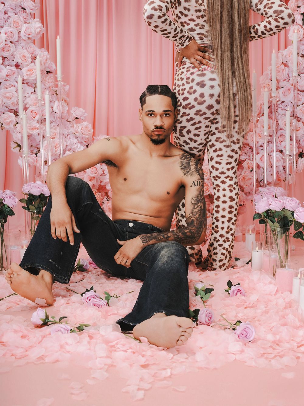 Artistic portrait in pink setting with leopard print decor, black jeans, and floral elements on pink backdrop.