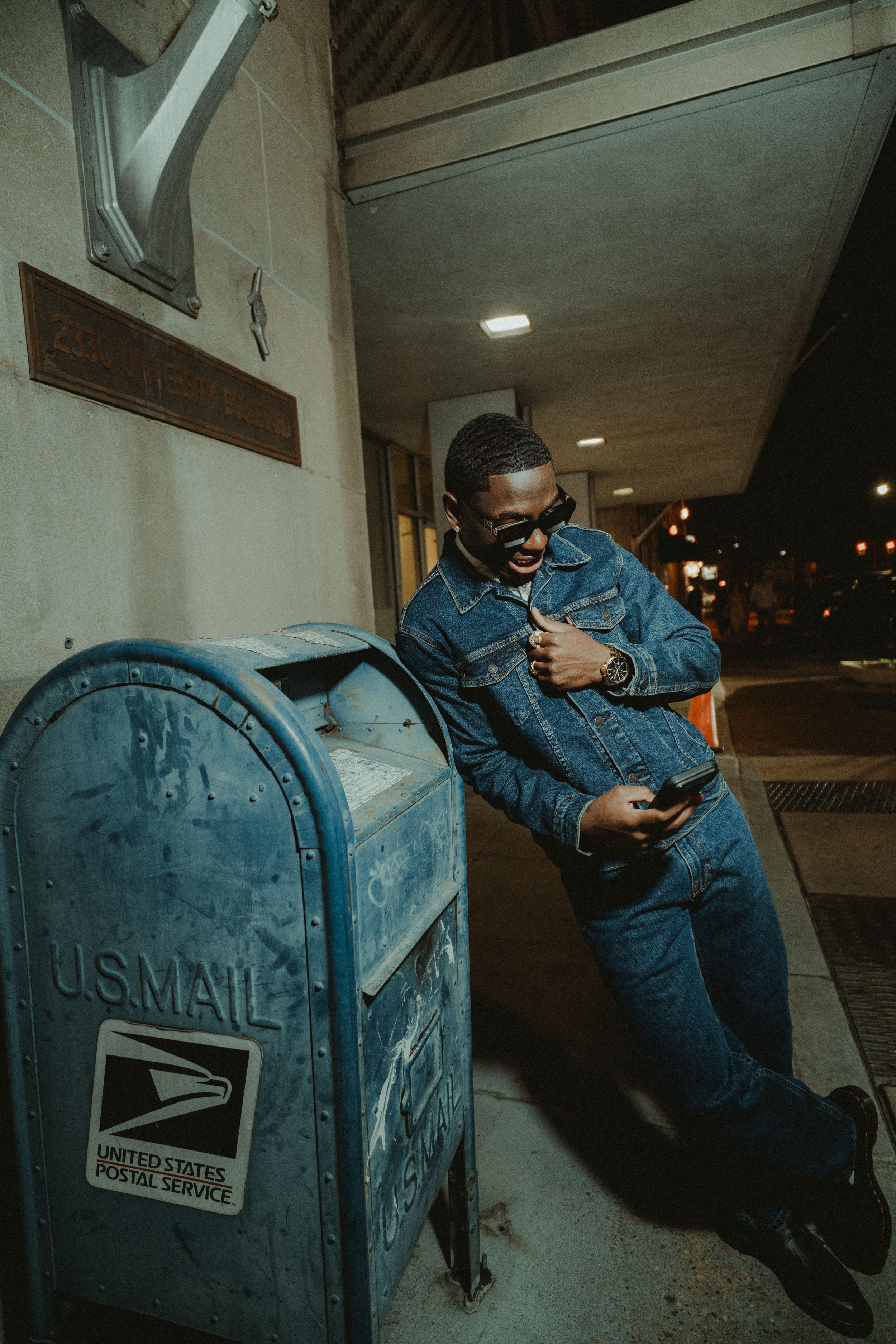 Four sequential photos show someone attempting to break into a blue US Postal Service mailbox at night.