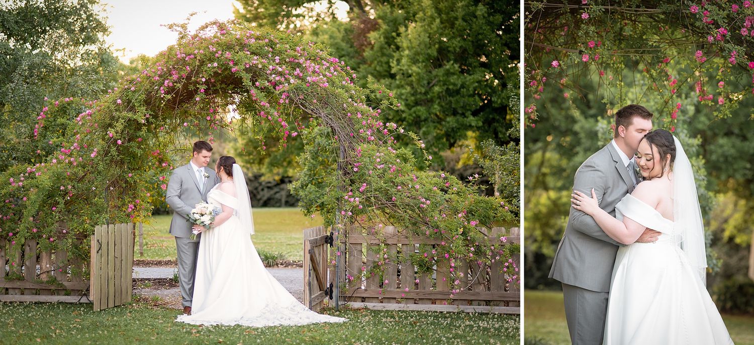 Bride and groom share a romantic moment under a floral arch at an outdoor wedding venue surrounded by lush greenery.