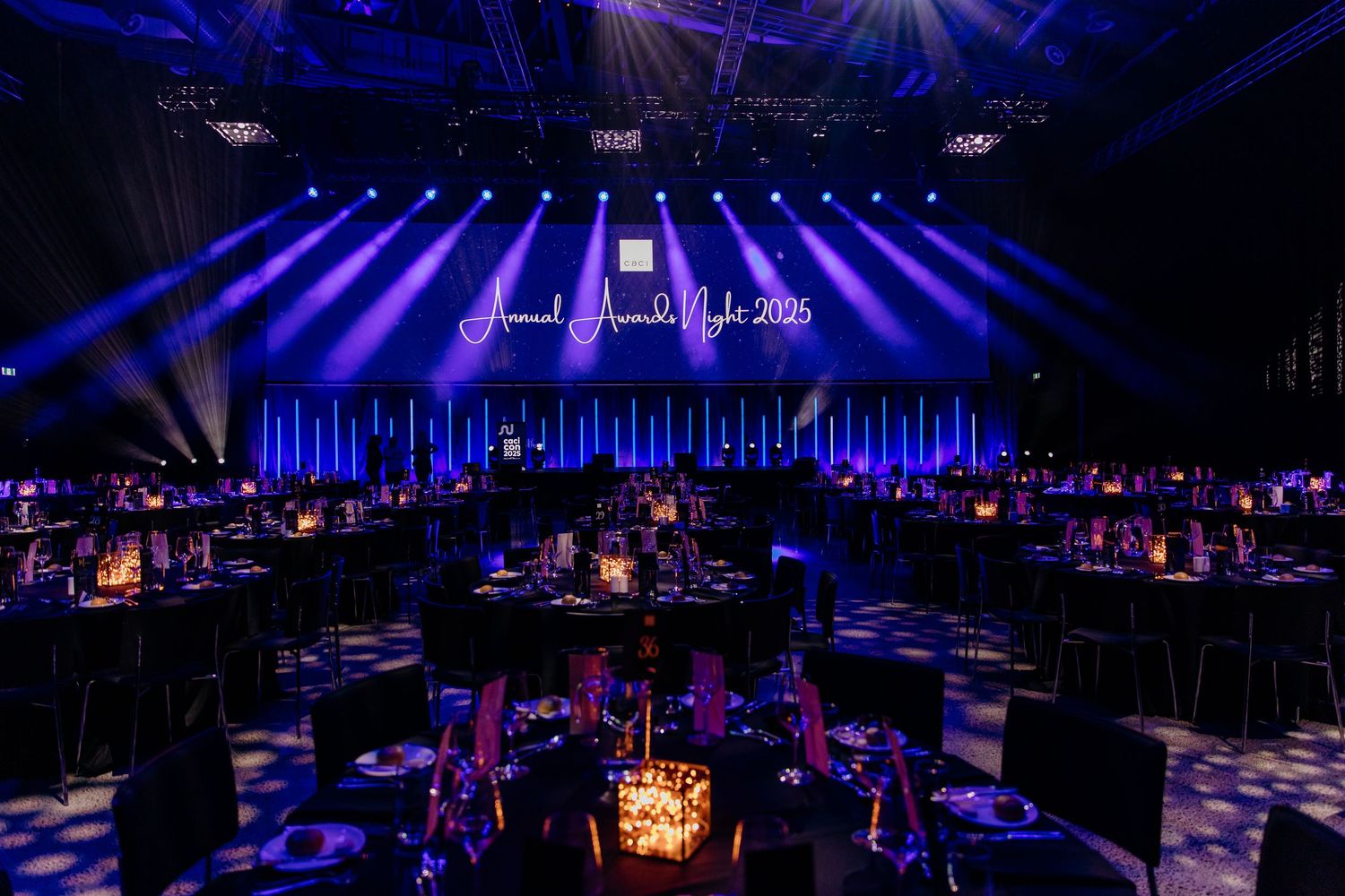 Event room set up with styled tables, dramatic lighting and client branding