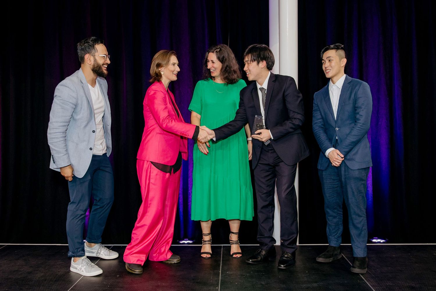 Presenters at a film festival on stage giving an award to a winner
