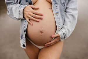 A denim-clad person gently cradles their pregnant belly in a series of touching maternity photos.