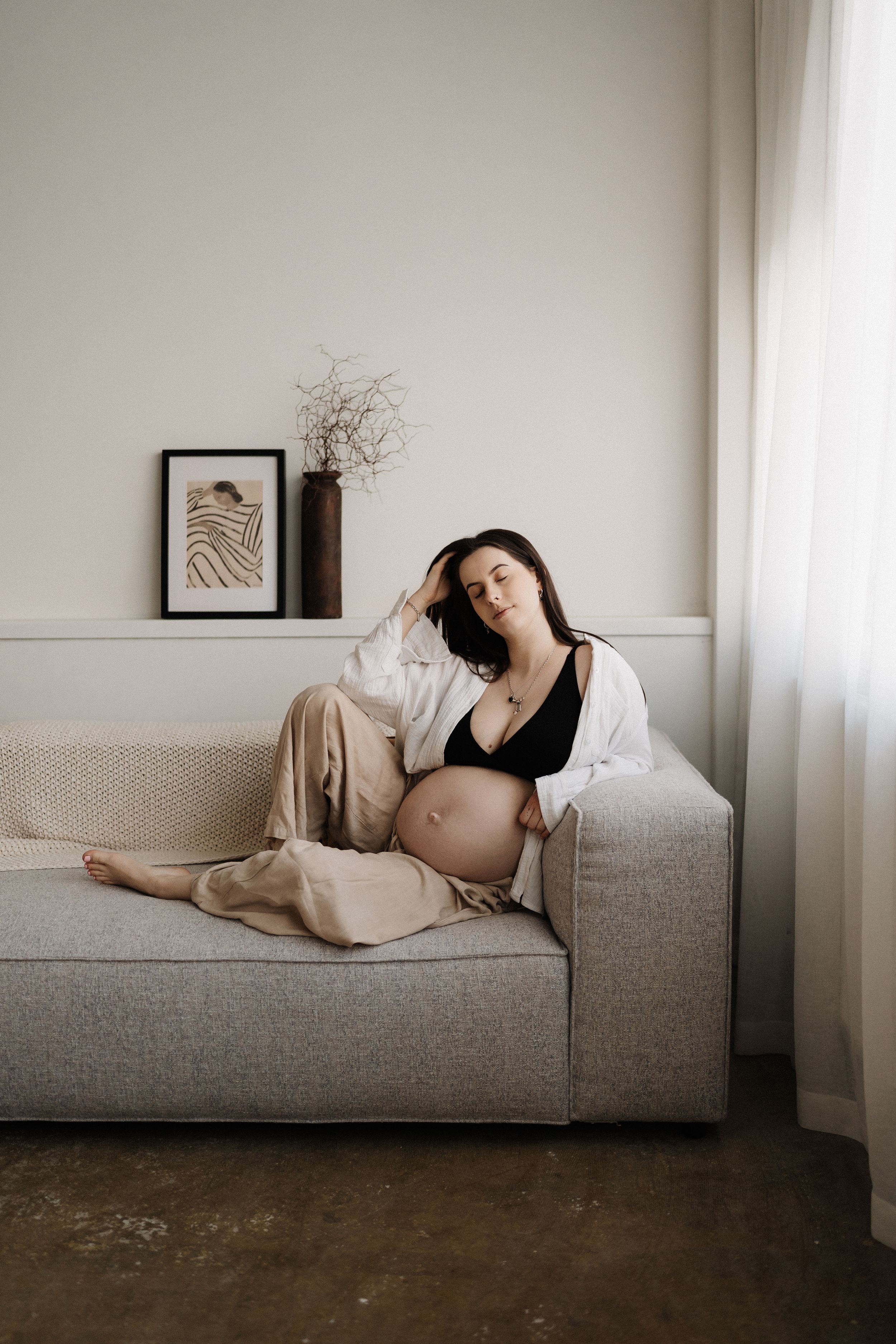 A series of artistic photographs showing a person reclining on a grey couch in a minimalist white room.