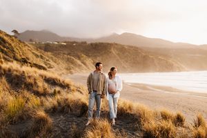 Couple walks along coastal cliffs at sunset with ocean views in the background.