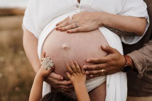 Close-up of hands touching pregnant belly during maternity photoshoot.