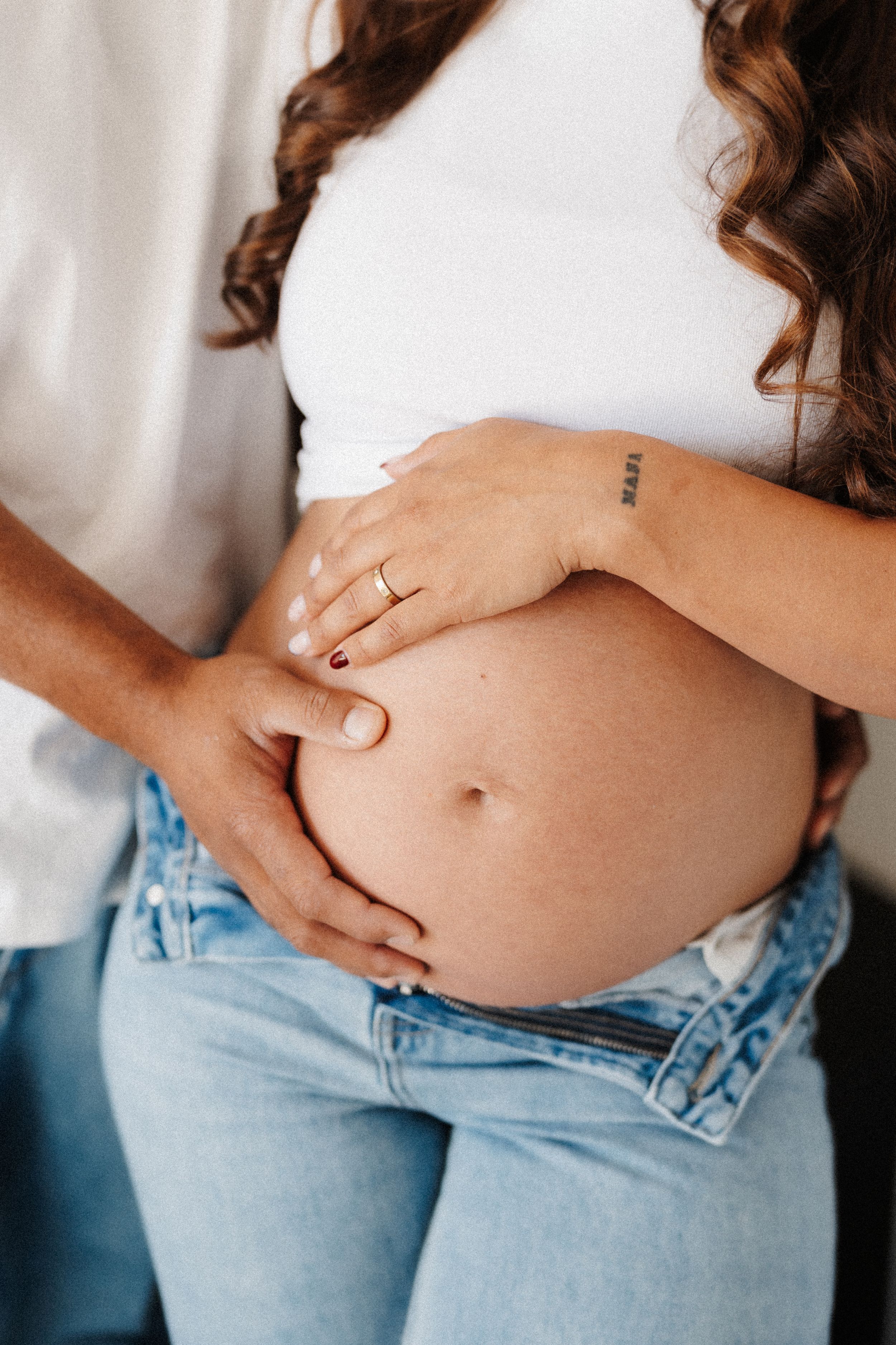 Close-up progression of a pregnant belly in light denim jeans showing growth over time.