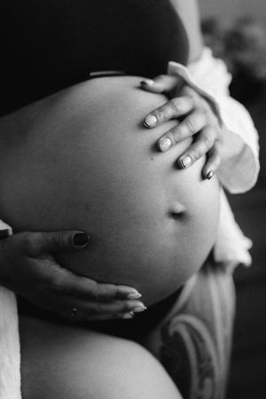 Black and white photo series showing hands gently cradling a pregnant belly in various intimate poses.