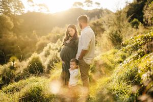 A family stands together on a sunlit hillside during golden hour.