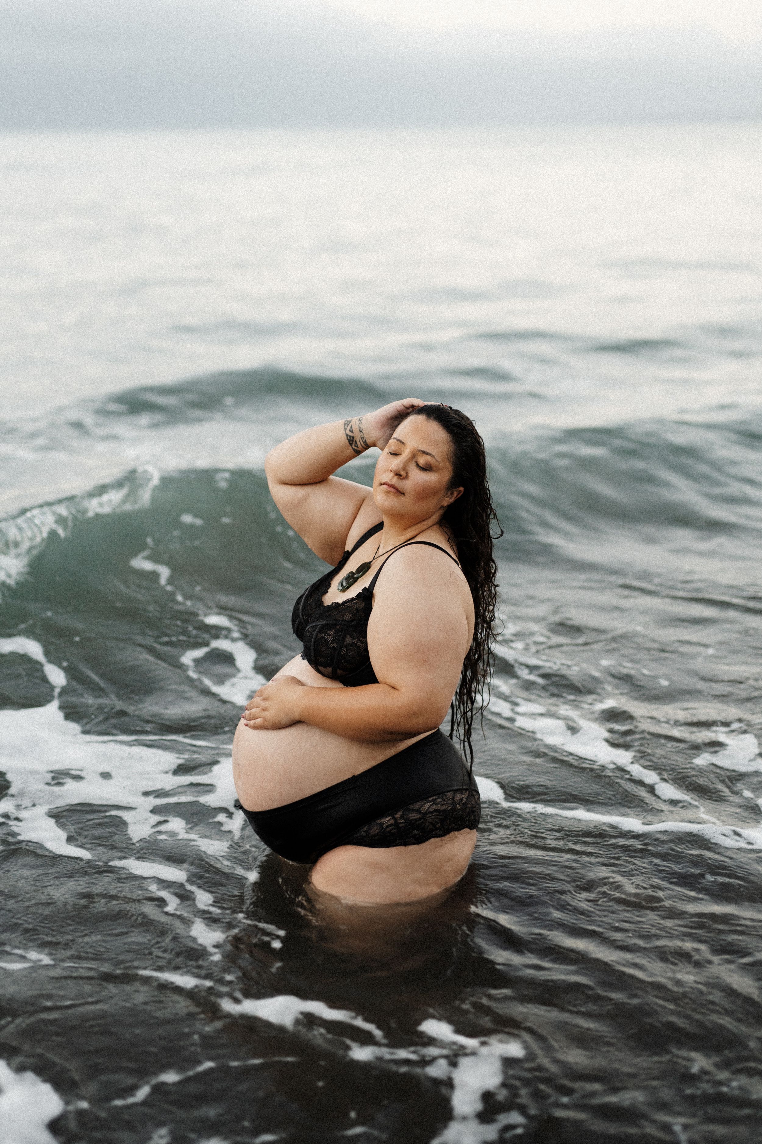 Person floating peacefully in ocean waves during an overcast day.