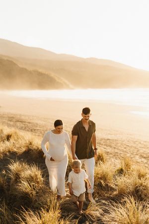 Family walking together on coastal hillside during golden hour.