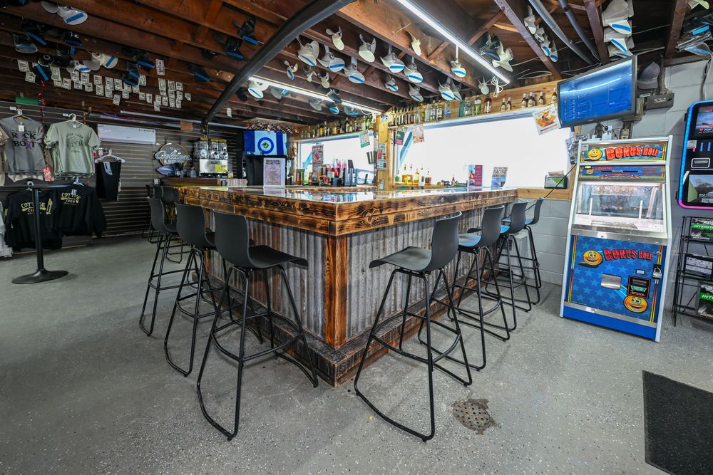 A horseshoe-shaped bar with gray stools, colorful mosaic counter, and arcade games in a casual retail space.