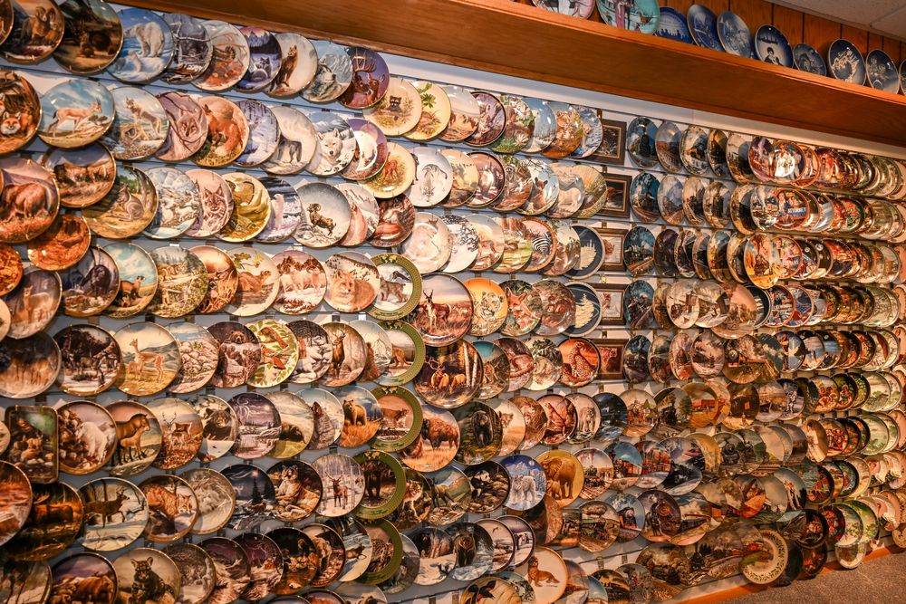 Wall display of colorful decorative collector plates arranged in rows at a gift shop or antique store.