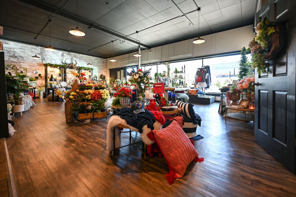 Cozy home decor store interior with colorful pillows, seasonal flowers, and holiday accents on hardwood floors.