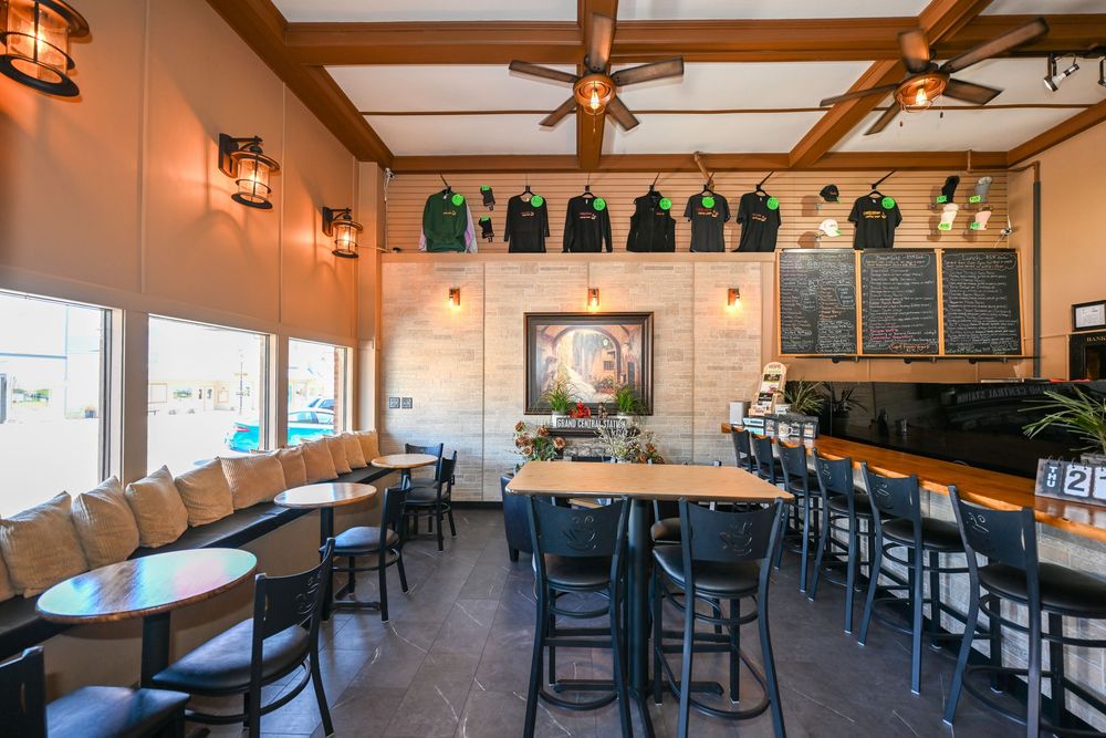 Cozy restaurant interior with black chairs, high-top bar seating, chalkboard menus, and green jerseys displayed on the wall.