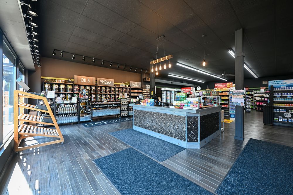 Modern retail store interior with checkout counter, wood flooring, blue carpet, and product displays under pendant lights.