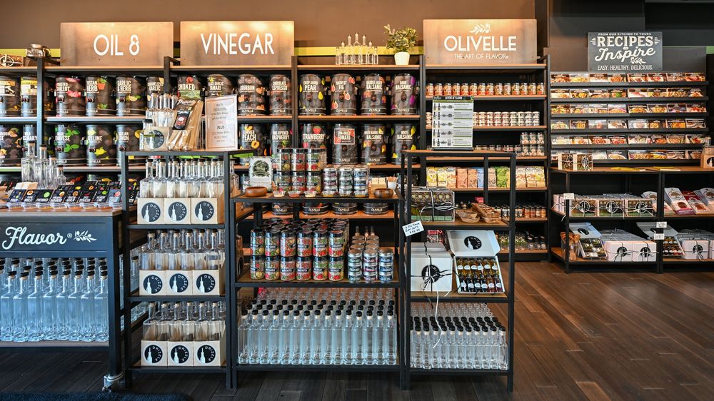 Gourmet specialty food store shelves stocked with vinegar, olive oil, and artisan products in an elegant retail display.