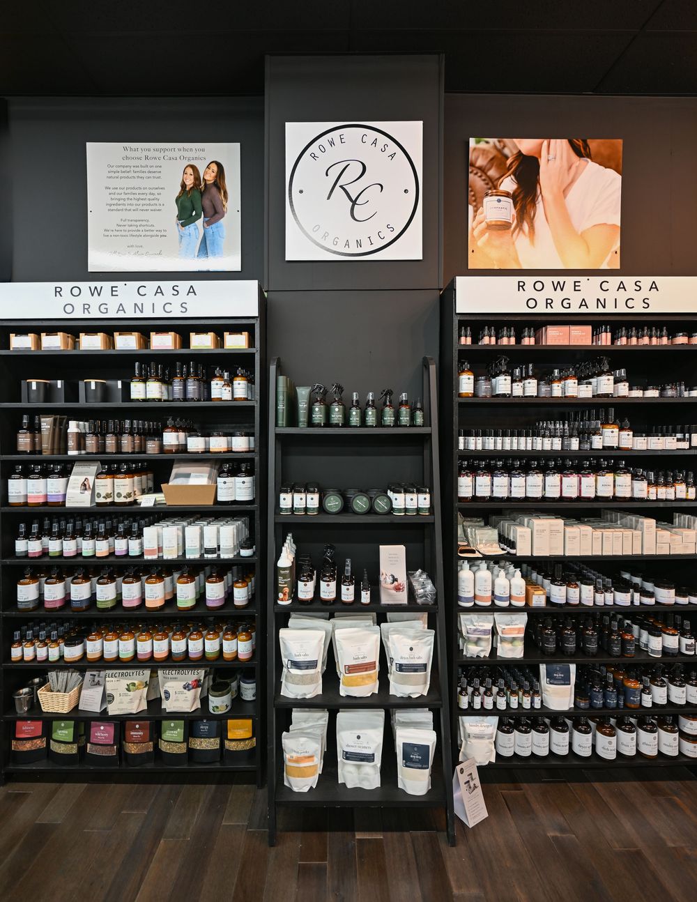 Rowe Casa Organics retail display shelves stocked with organic skincare products, essential oils, and supplements in a modern store.