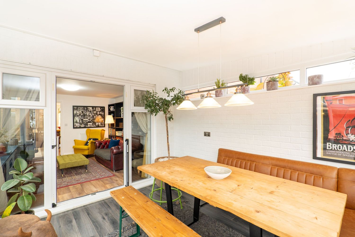 Bright modern dining space with wooden table and built-in seating near glass partition.