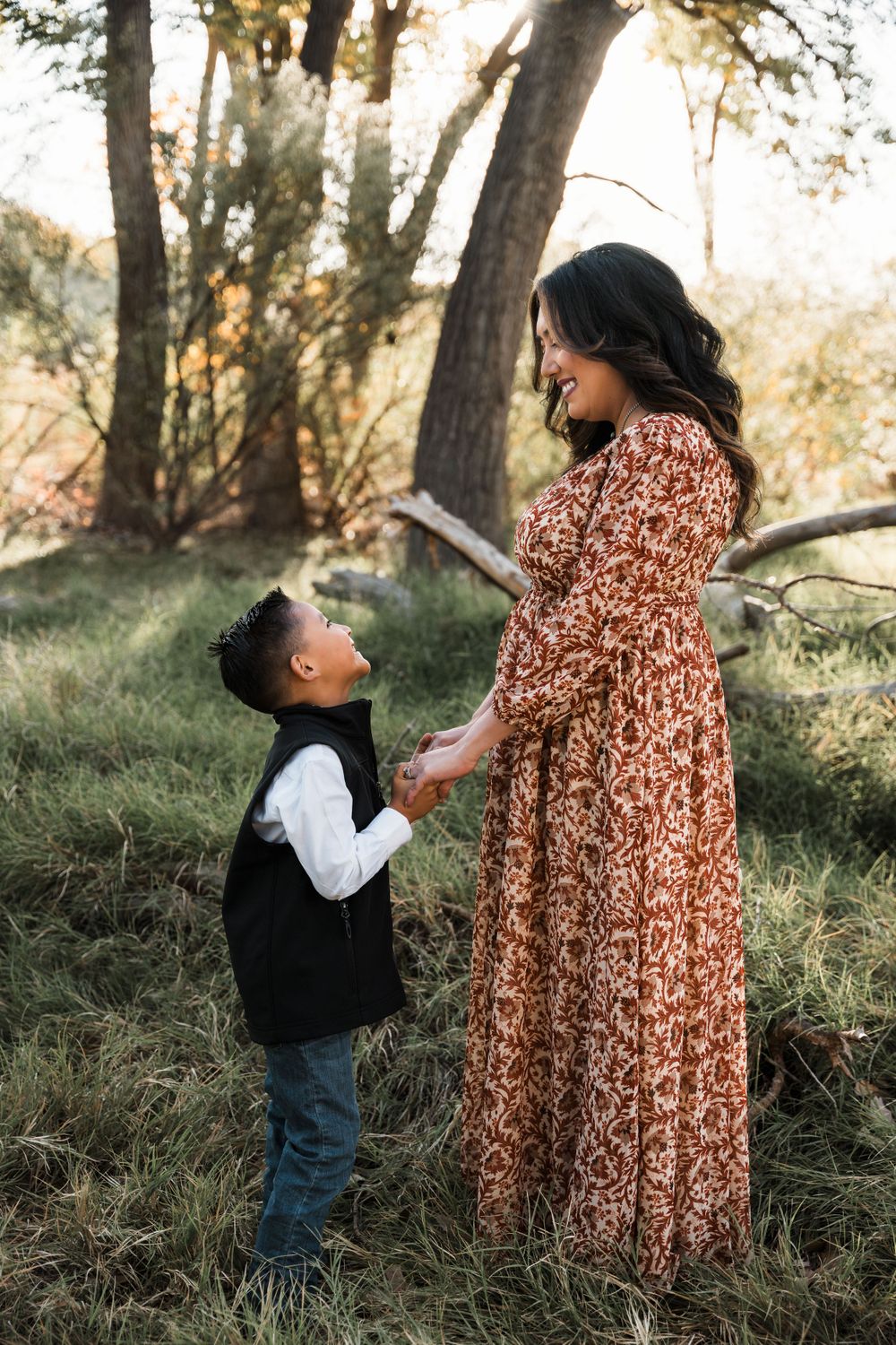 Tender moment between two people in floral dress and vest during outdoor autumn photo session.