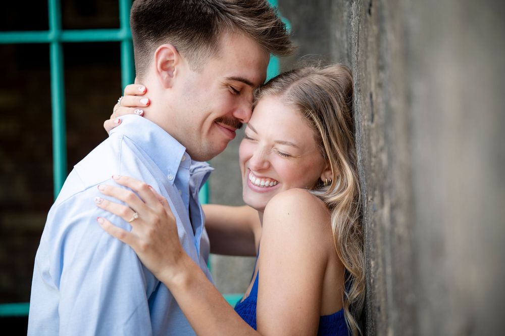 Intimate moment captured against rustic wall with turquoise window.