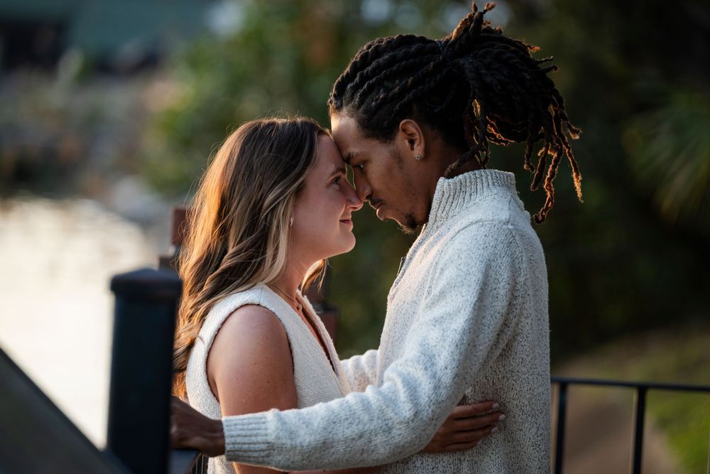 An intimate moment between a couple sharing an embrace on a balcony at dusk.