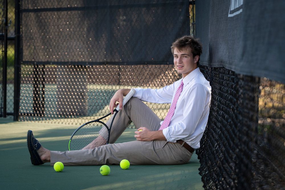 Tennis player rests on court with balls scattered around.